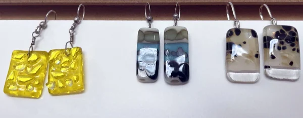 A collection of three unique rectangular glass earrings with various patterns and colors, each pair made at the Glass Duchess Studio in Port Charlotte, FL