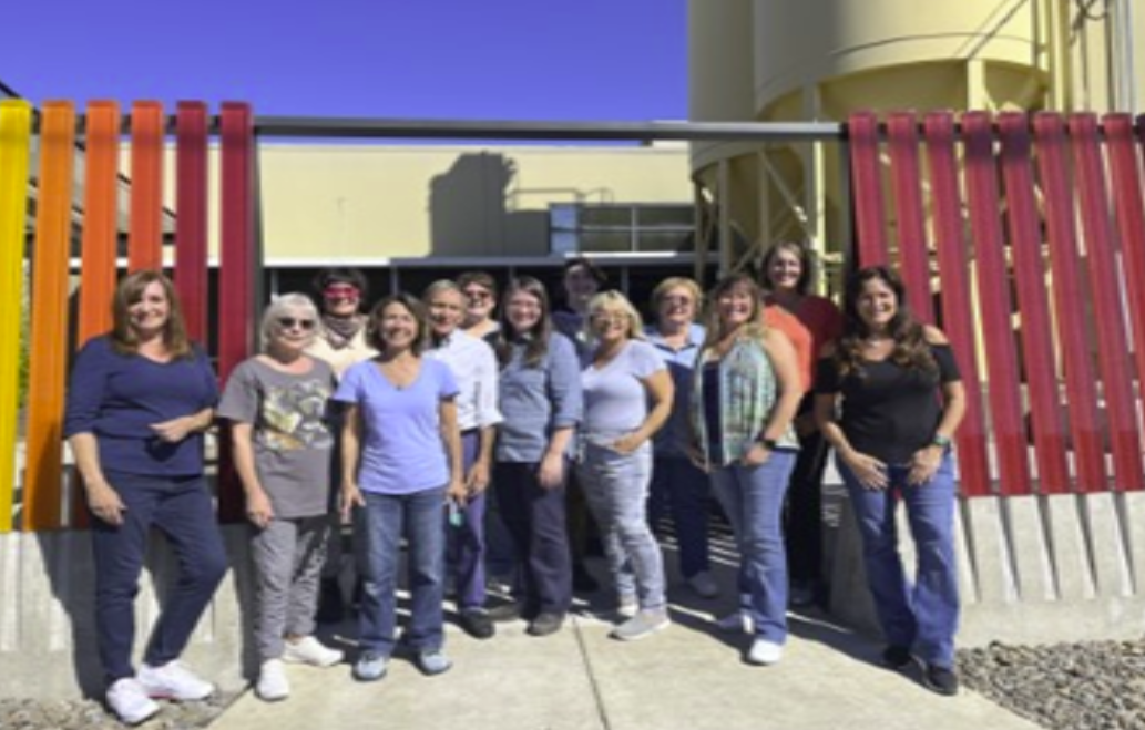 Group of people posing outside a colorful building.